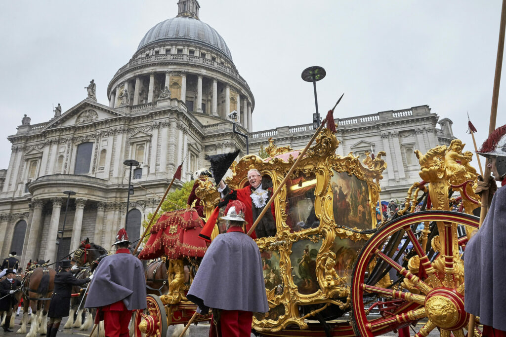 Man leaning out of a gold carriage with St Paul's Cathedral behind