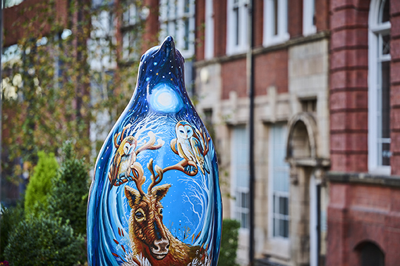 Blue sculpture of a penguin on the street