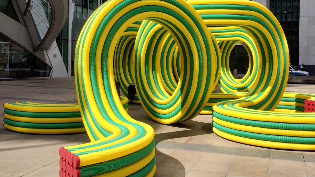 Outdoor art installation - yellow and green pipes, with red decoration.