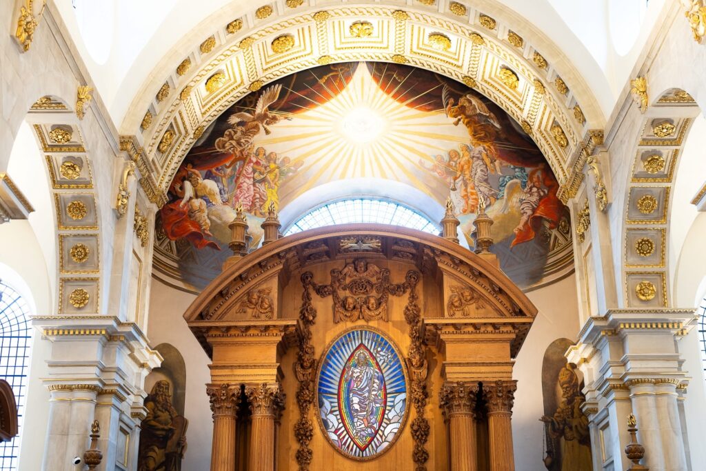 Interior of St Bride's Church - white walls with decorative elements, and stained glass.