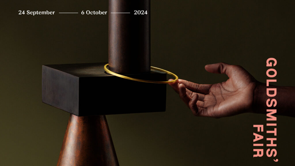 Promotional image for the Goldsmiths' Fair 2024, featuring a close-up of a hand poised near a sculptural jewellery piece on display, with event dates from 24 September to 6 October.