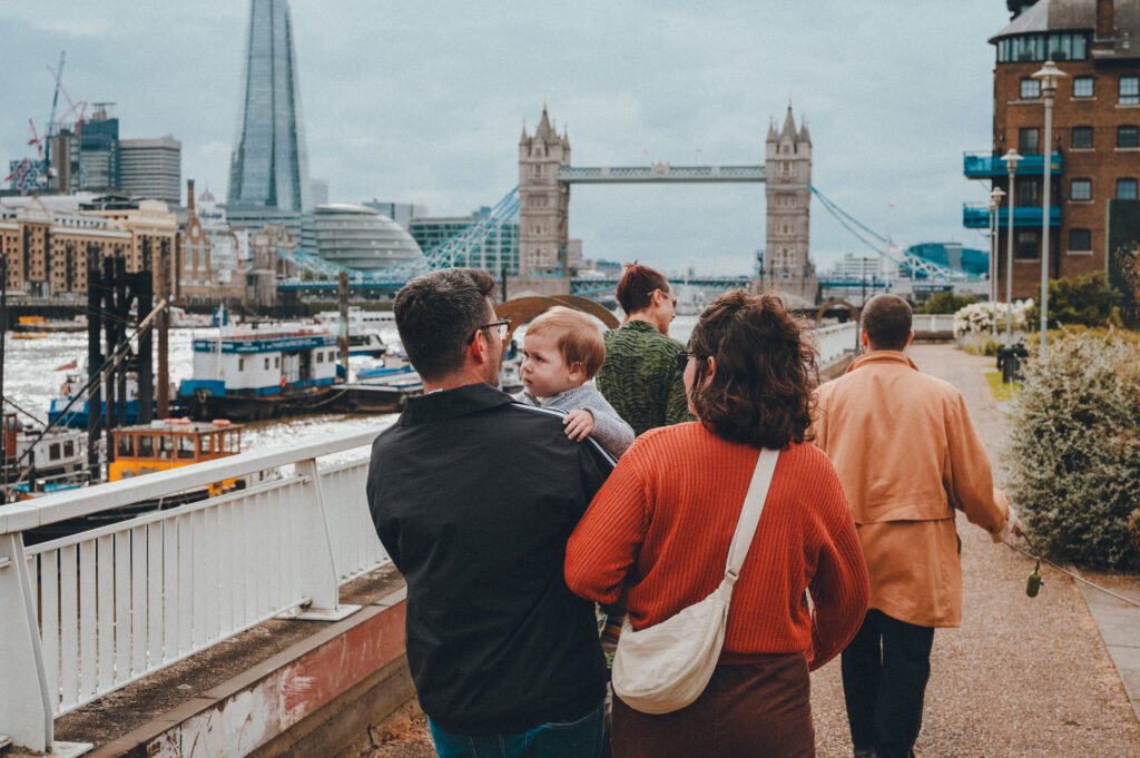 Group of people walking along the riverside in London with Tower Bridge in the background.