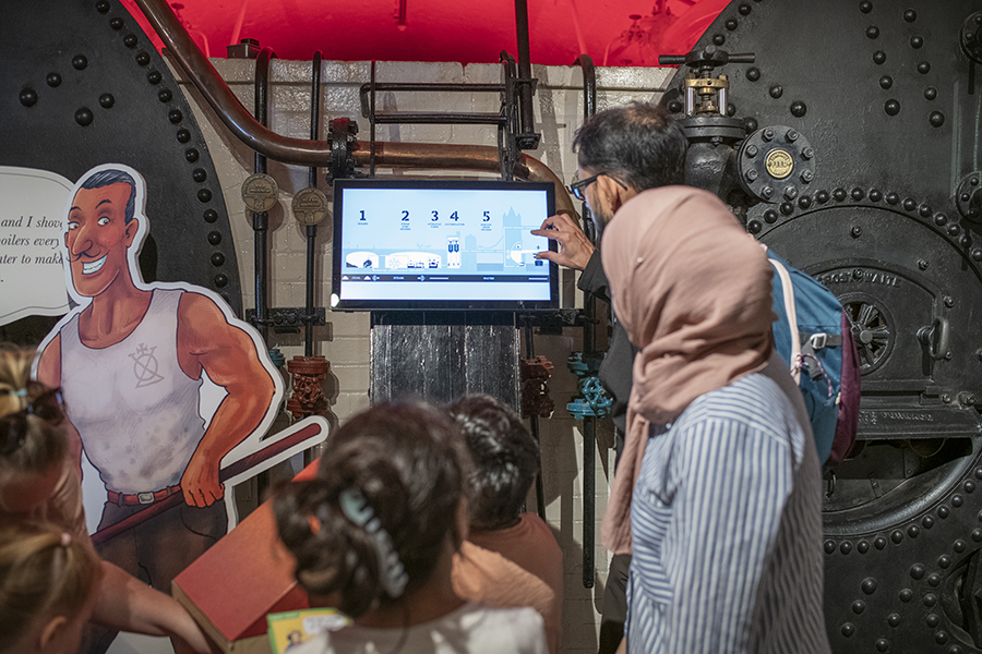 Children and two adults looking at a screen in a museum