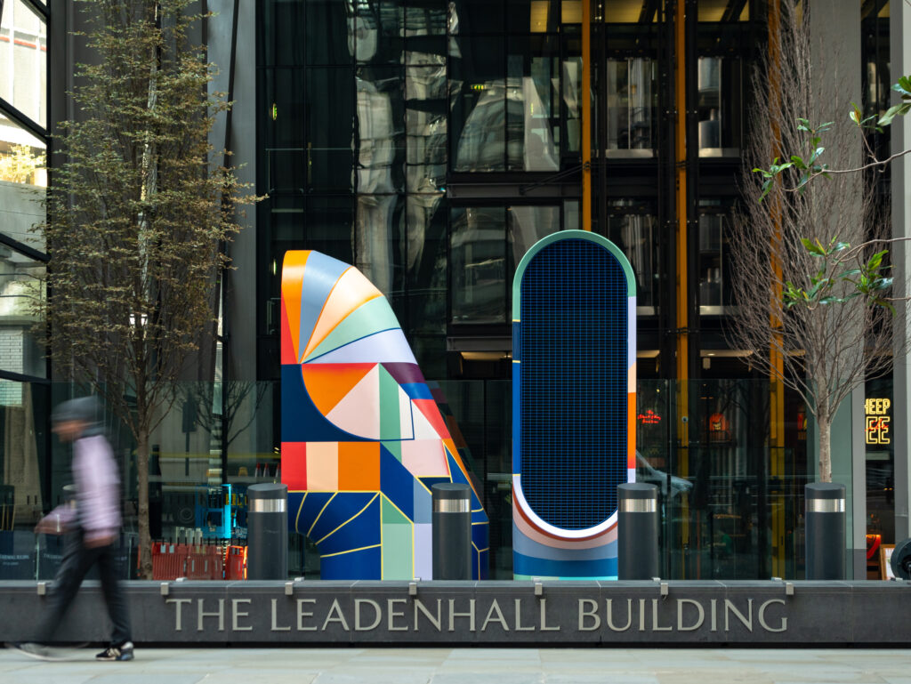 Colorful abstract mural in front of The Leadenhall Building with a blurred figure walking by.