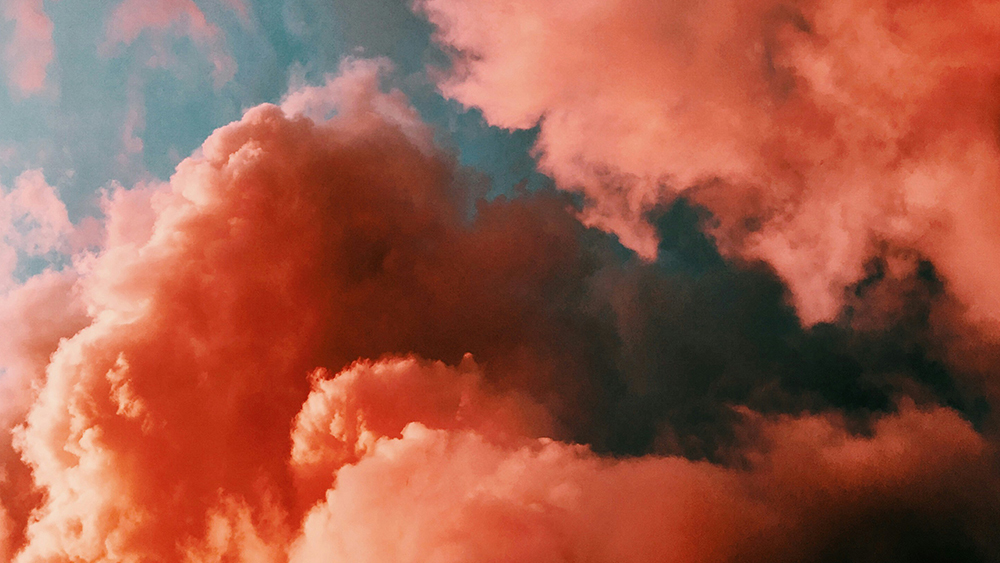 Vibrant pink and orange clouds against a soft blue sky at sunset.