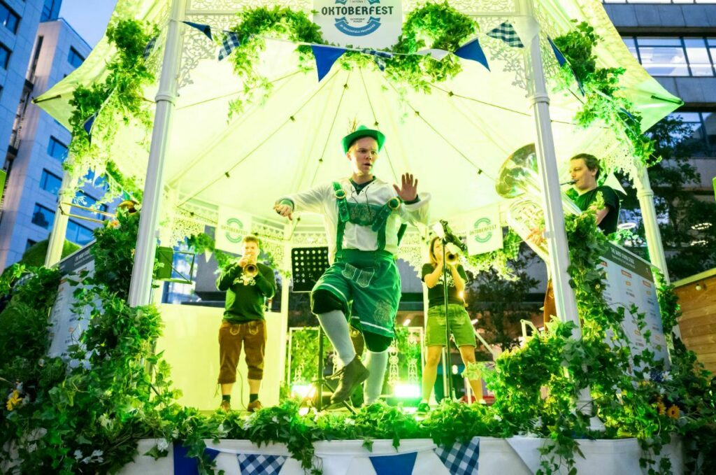 Participants in traditional Bavarian outfits perform on a festively decorated stage at Oktoberfest.