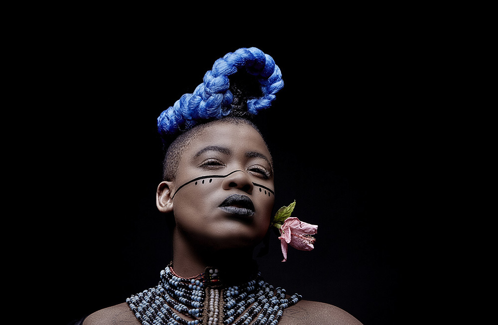 A woman with striking blue hair and a black line drawn across her face, showcasing a unique and bold artistic expression.