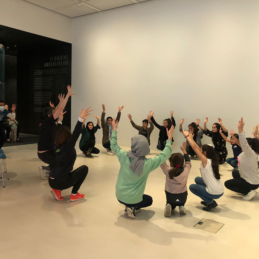 A group of people squatting with their hands in the air and a museum