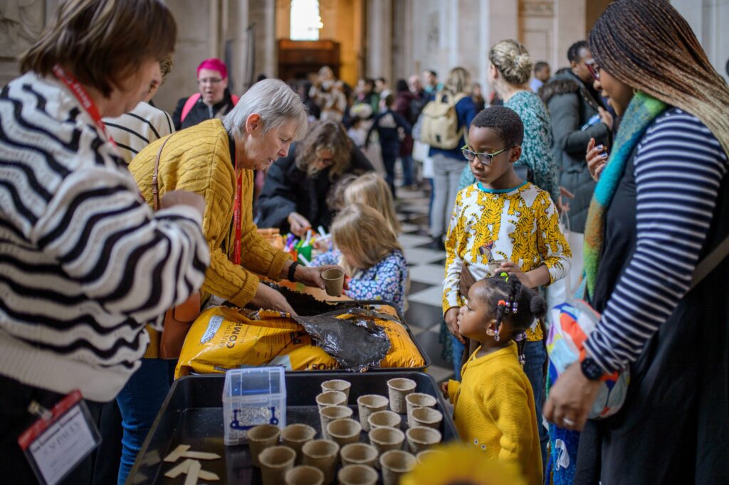 Visitors of various ages engage in a hands-on educational activity at a well-attended public event inside St Paul's Cathederal.